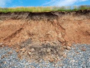 Close-up of soil erosion and instability near a mountain home in Sevierville, emphasizing the need for thorough home inspections in hilly areas.