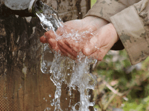 Hands collecting water from an outdoor spigot in Gatlinburg TN, illustrating water quality and flow during a home inspection